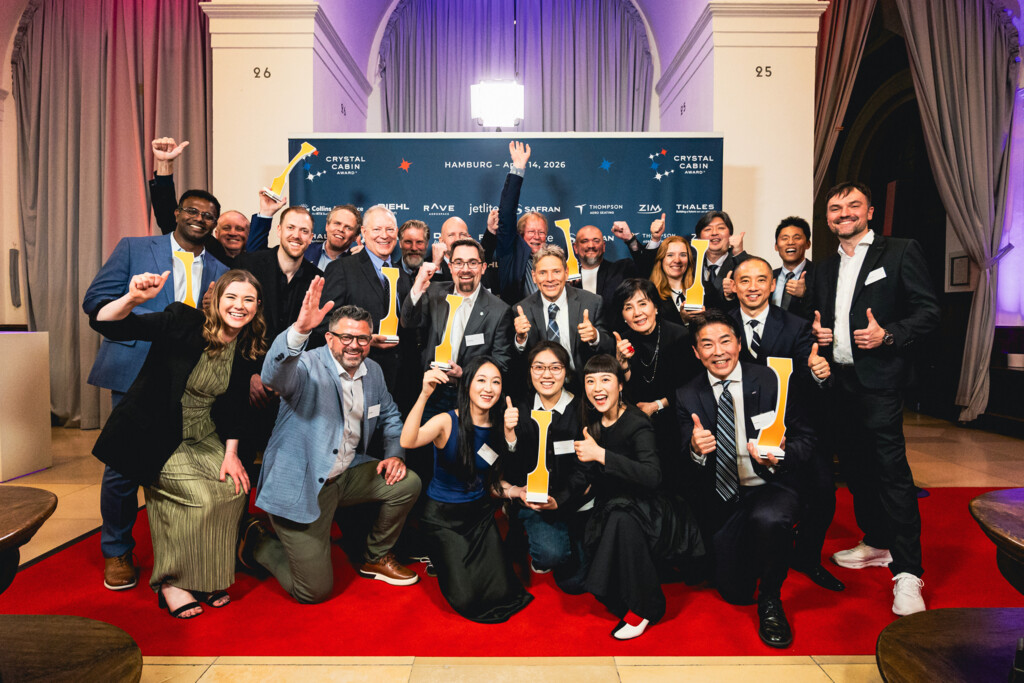 Gruppenfoto von jubelnden Menschen mit Auszeichnungen auf rotem Teppich bei Crystal Cabin Award 2026 in Hamburg.