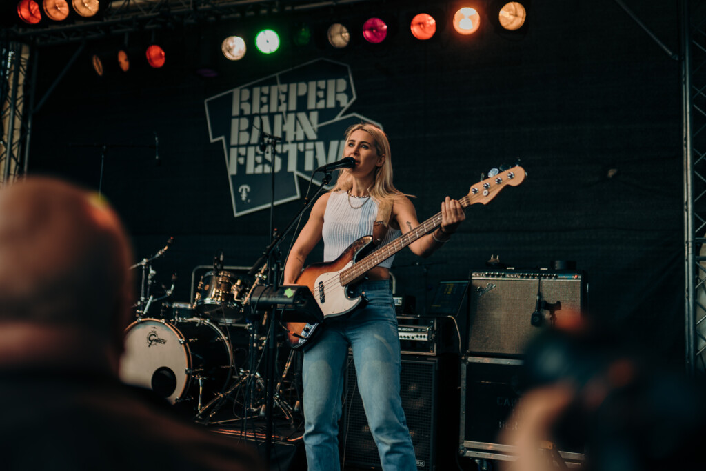 Musikerin spielt E-Bass und singt auf der Bühne beim Reeperbahn Festival vor Publikum.