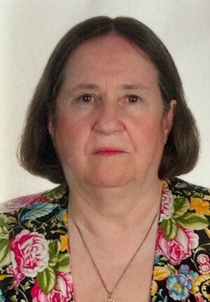 Portrait of an older woman with shoulder-length grey hair and a patterned top.