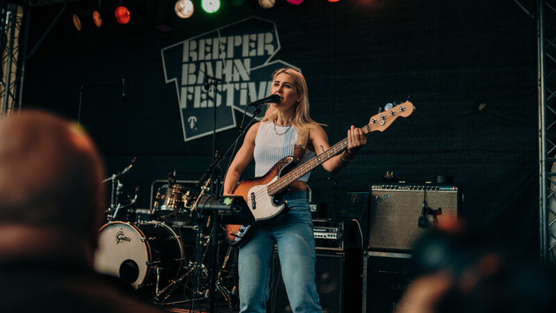 Eine Musikerin spielt Bass und singt auf der Bühne des Reeperbahn Festivals.