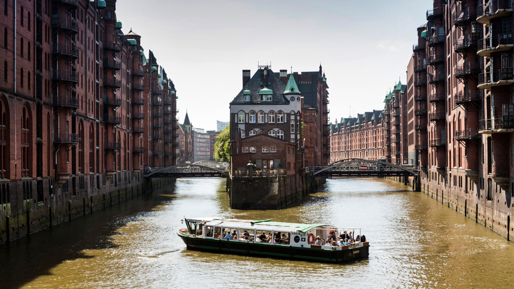 Blick auf die Speicherstadt in Hamburg mit einem Ausflugsboot auf dem Wasserkanal.