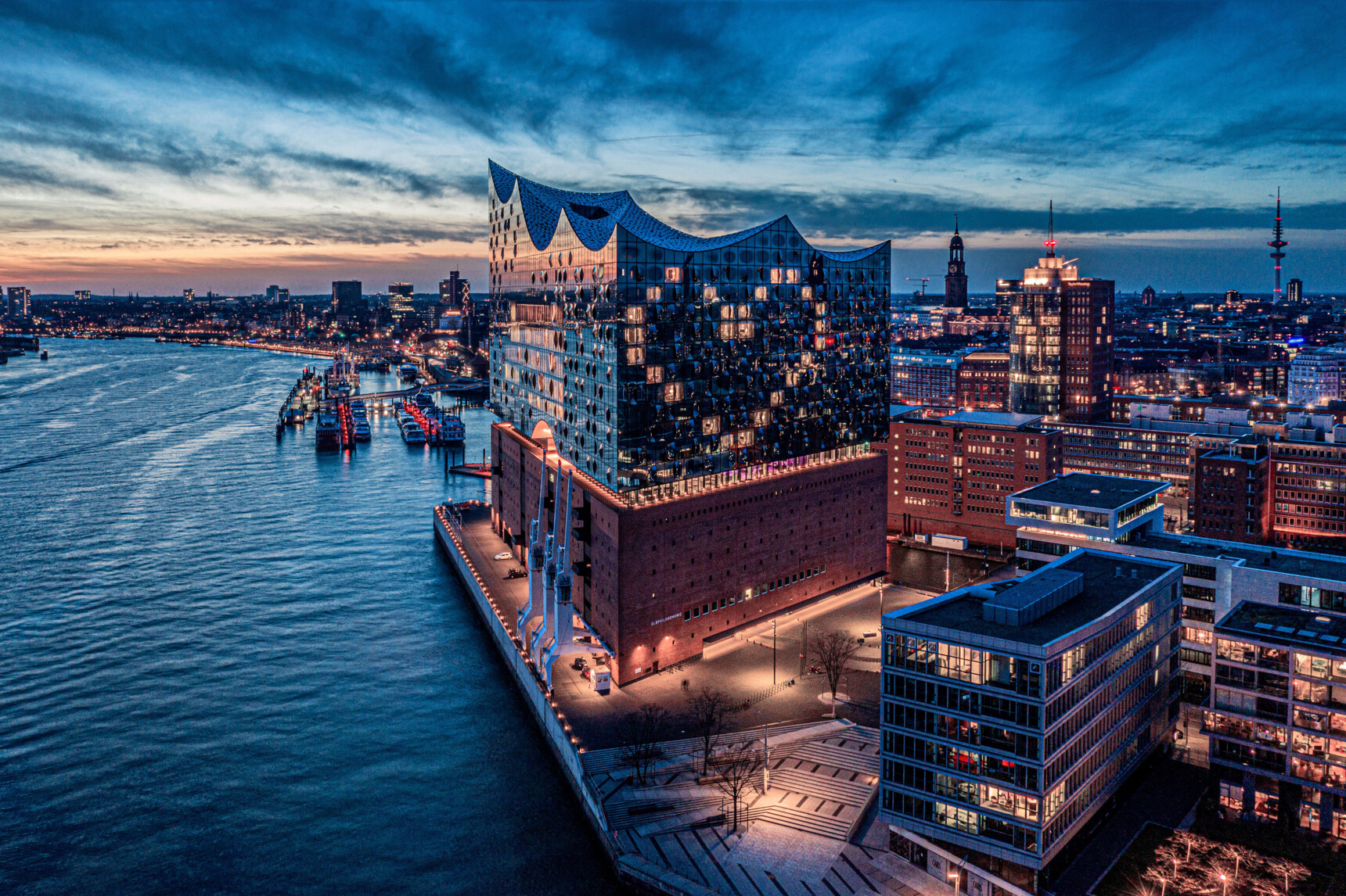 Blick auf die Elbphilharmonie und den Hamburger Hafen bei Abenddämmerung.