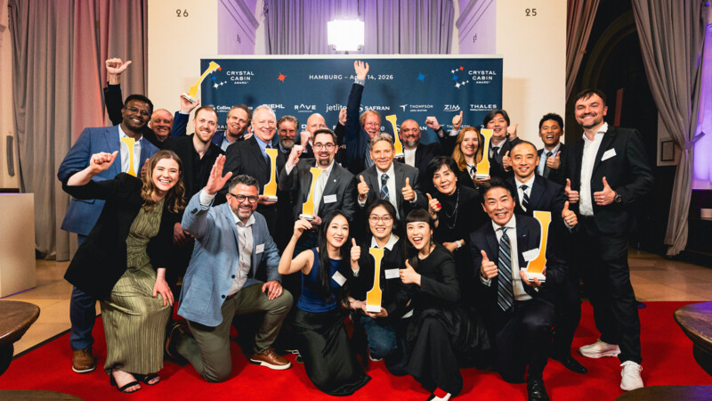 Gruppenfoto von jubelnden Menschen mit Auszeichnungen auf rotem Teppich bei Crystal Cabin Award in Hamburg.