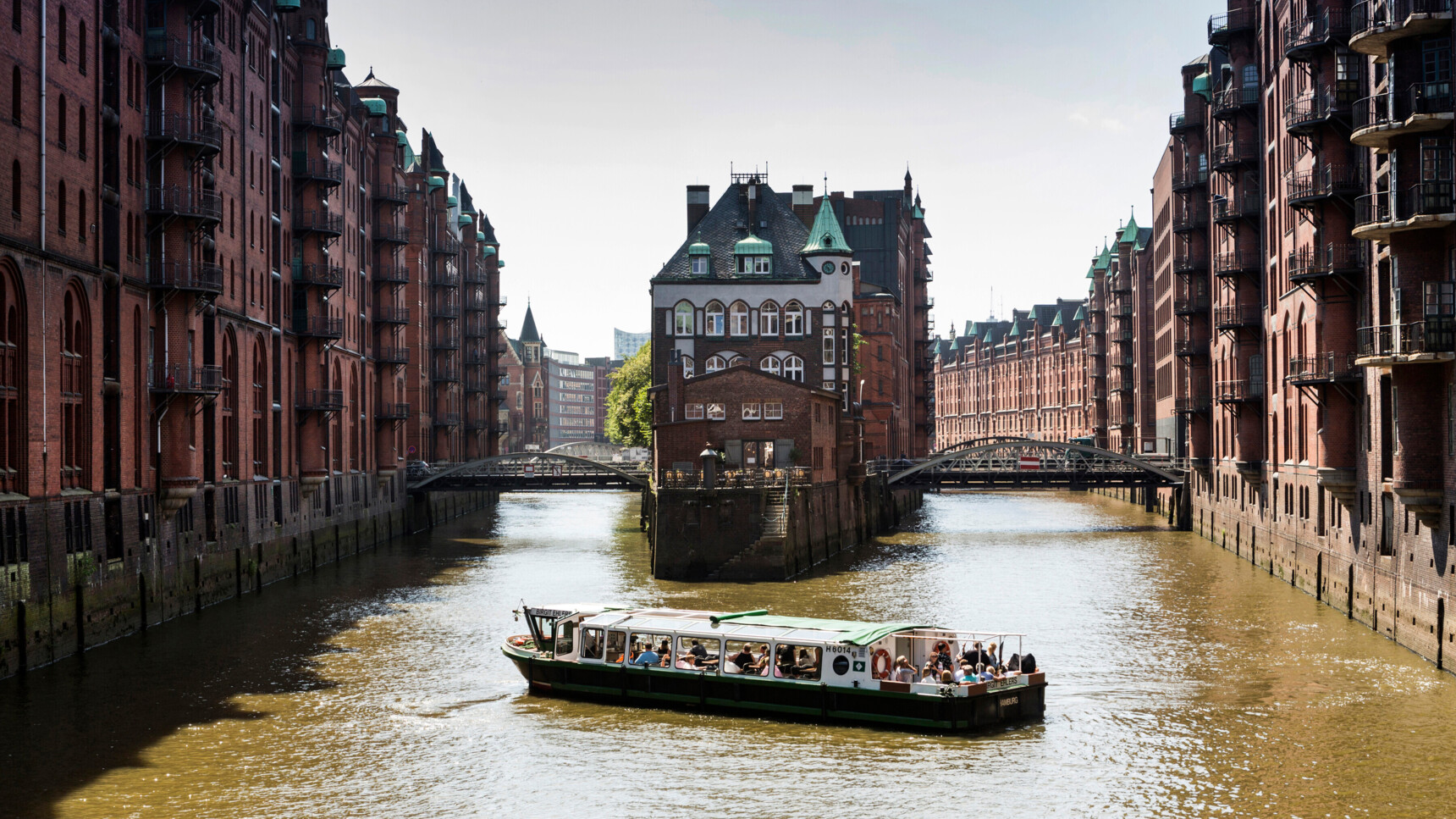 Blick auf ein historisches Backsteingebäude und eine Bootstour durch die Hamburger Speicherstadt.