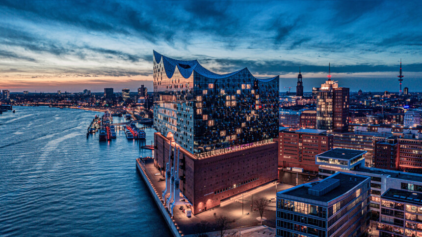Evening aerial view of the illuminated Elbphilharmonie concert hall by the river in Hamburg, Germany.