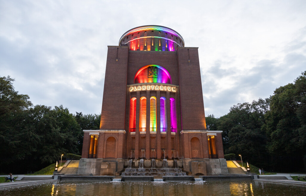 Das Planetarium Hamburg leuchtet bei Abenddämmerung in bunten Regenbogenfarben.
